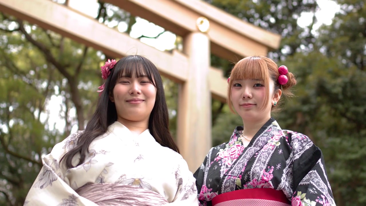 Inquadratura dal basso di due donne giapponesi sorridenti che indossano kimono tradizionali all'ingresso di un santuario