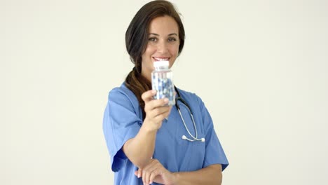 Young-brown-haired-doctor-in-scrubs-holds-bottle