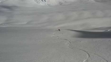 4k drone footage of snowboarder going down big empty slope
