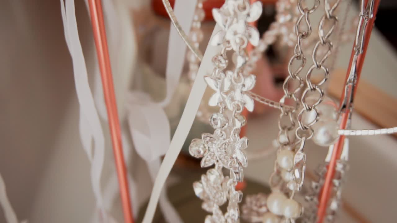 Joias de cabeça prateadas e douradas com pérolas para noivas, penduradas em um suporte de cobre moderno e elegante na loja.
