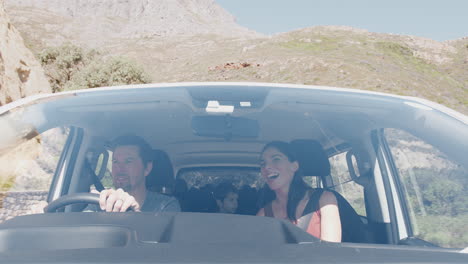 vista desde el exterior del vehículo como coche de conducción familiar a lo largo de la carretera de montaña al destino de vacaciones