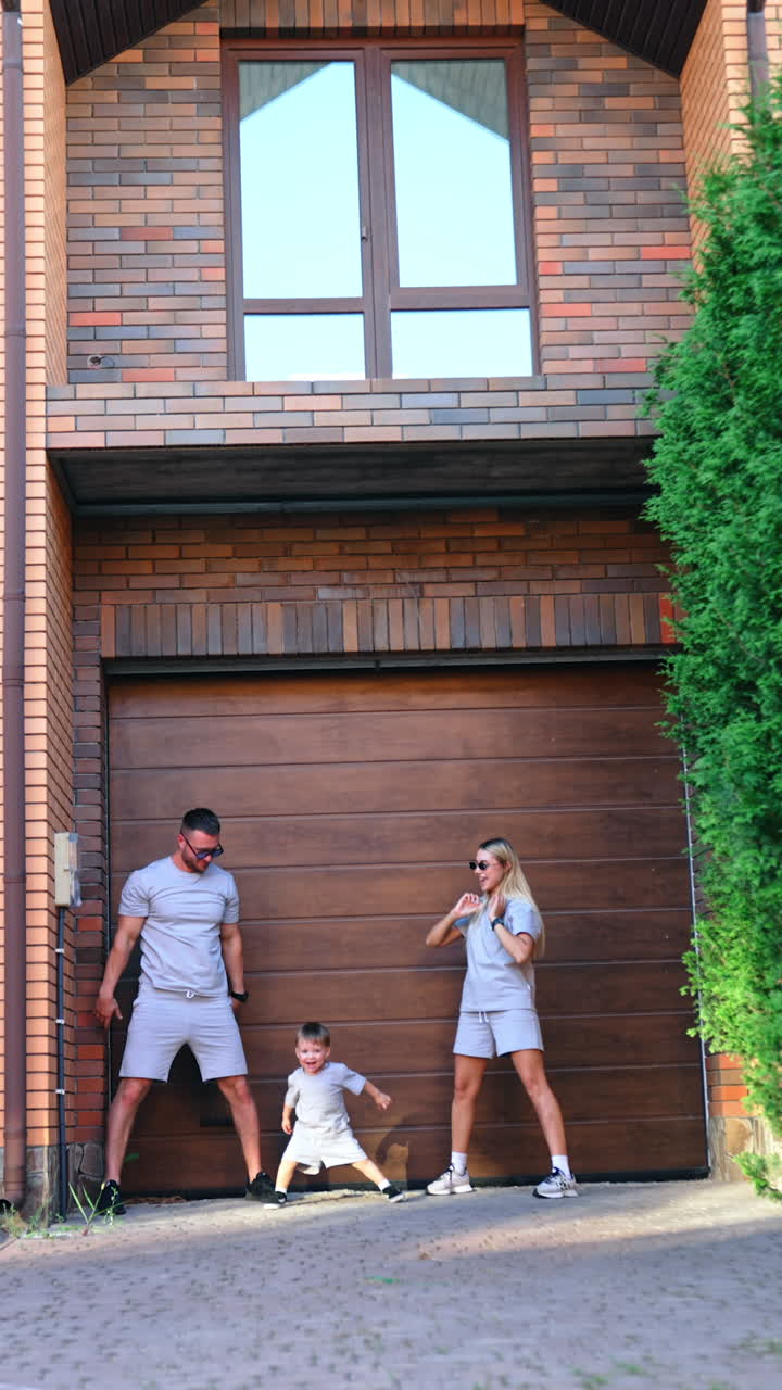 Happy family stand at the wooden door to a garage. Parents show how to jump to their kid. Vertical video