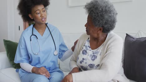 caring african american female doctor and sad senior female talking