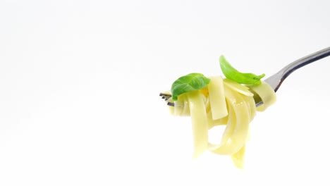 Close-up-of-cooked-pasta-with-basil-on-fork