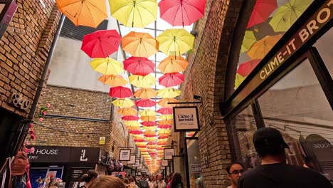 people walking under vibrant umbrellas in camden market