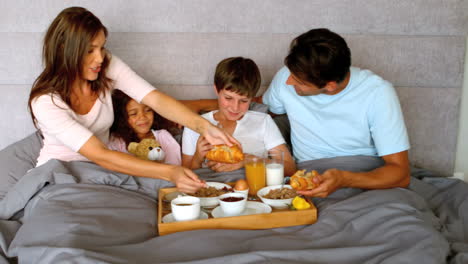 Family-having-breakfast-in-bed