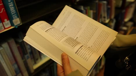 person flipping through book in library