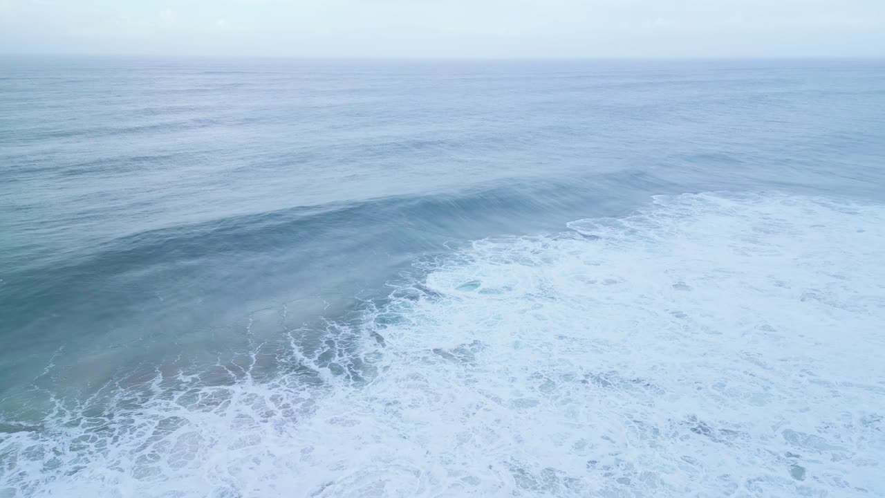 Calm ocean waves breaking gently near shore in Aljezur, Portugal at sunrise