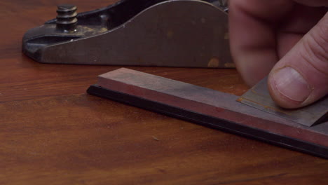 man sharpens wood plane blade on countertop whetstone, close-up view