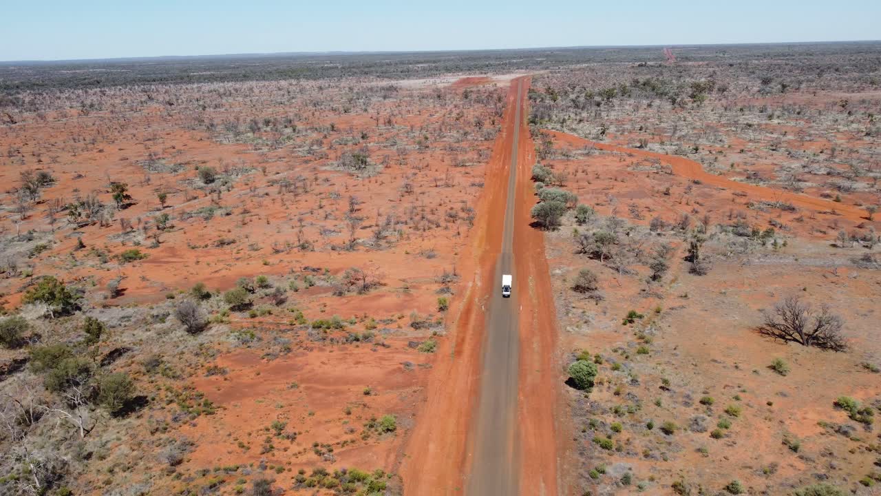 vista aérea de una carretera de campo sellada mientras un coche remolca una caravana que pasa por el interior de australia