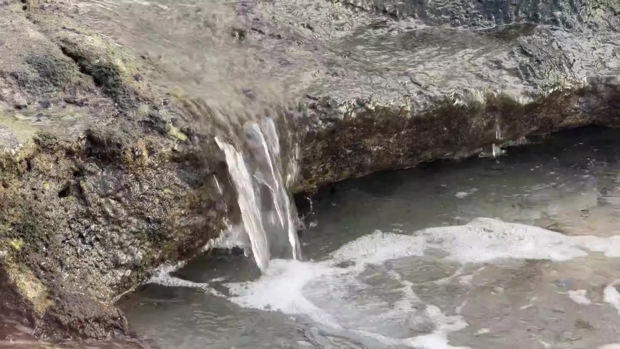 Pequena Cachoeira Fluindo sobre Rochas Musgosas em uma Lagoa