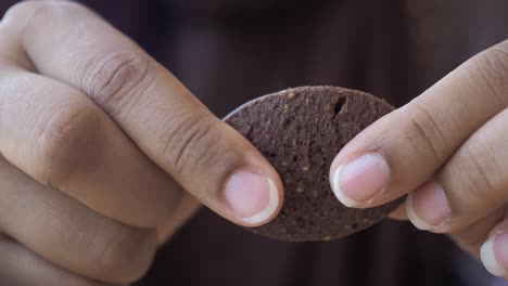 close-up of hands breaking a chocolate cookie in half