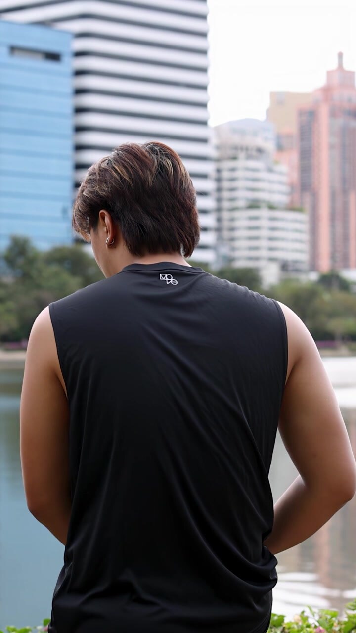 Rear view of an athletic man stretching his arms in a park with city skyline