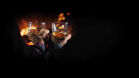 Hands-Of-Two-Men-With-Glasses-Of-Whiskey-On-The-Background-Of-The-Fireplace-Male-Rest