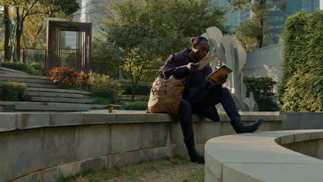 man reading tablet in urban park
