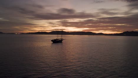 slowmotion shot of an anchored boat in the ocean off the coast of malaysia with the sun setting behind