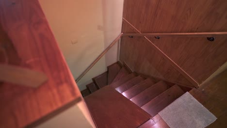 slow right panning downward camera view of wooden house stairs, with yellow and wooded walls and interior lighting. shot on 4k.