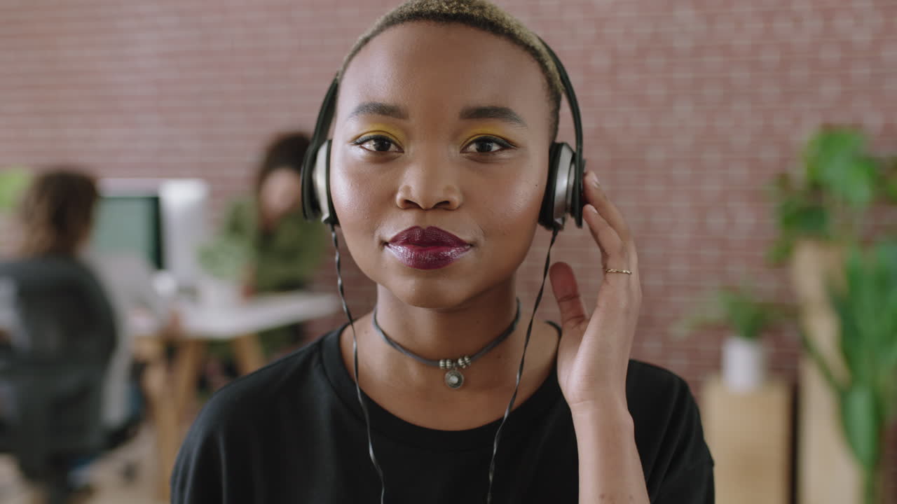retrato de una joven afroamericana de moda con auriculares escuchando música en un espacio de trabajo de oficina moderno