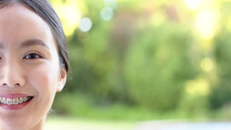 smiling asian girl with braces enjoying outdoors, close-up portrait in natural light, copy space