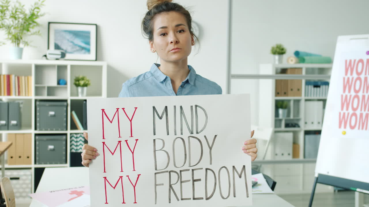 Woman Holding a Poster with the words "My Mind My Body My Freedom" in an Office Setting.