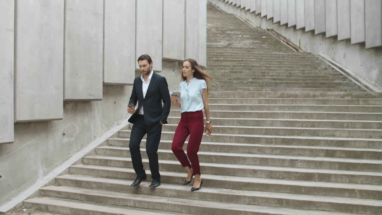 compañeros confiados bajando las escaleras. hombre y mujer hablando en la calle