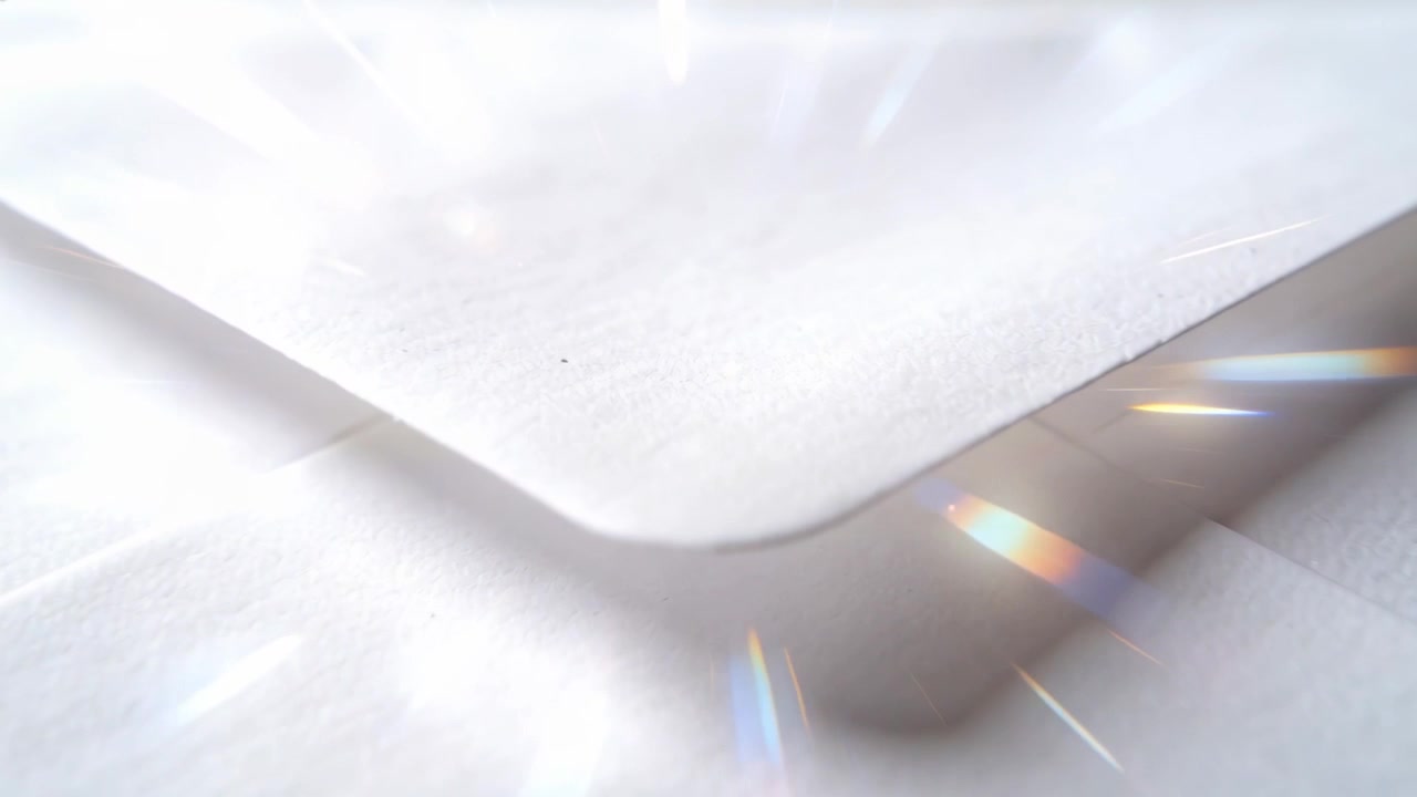 Moving camera examining white envelope V-flap on reflective table, showing sheet beneath and flares