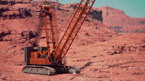 a large orange crane is parked in a desert canyon