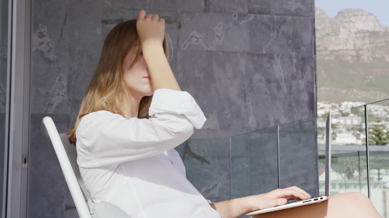 mujer caucásica usando una tableta digital en el balcón