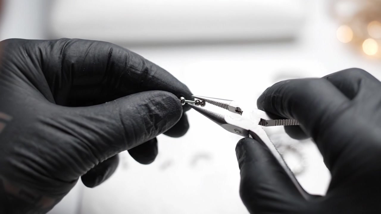 Artesão realizando trabalho artesanal intrincado usando alicates e pequenos componentes metálicos em uma oficina criativa prática para montagem detalhada e aprimoramento de design