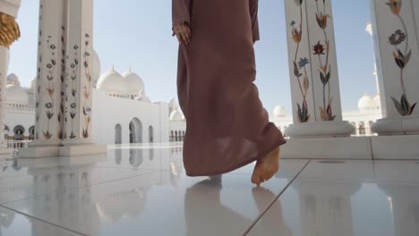 muslim in abaya enter mosque hall with white marble floor, uae