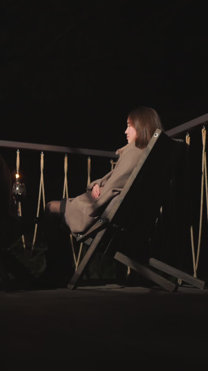 Man and woman sit near low table with candles. Couple has romantic vacation together in country cottage in autumn. Date between man and woman with wine