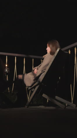man and woman sit near low table with candles. couple has romantic vacation together in country cottage in autumn. date between man and woman with wine