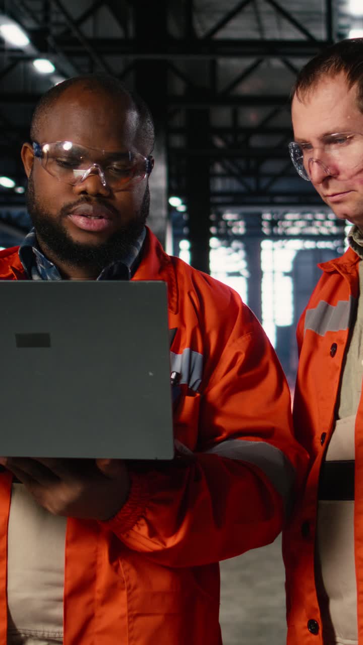Vertical Video Diverse operators use laptop to coordinate production activity on factory floor