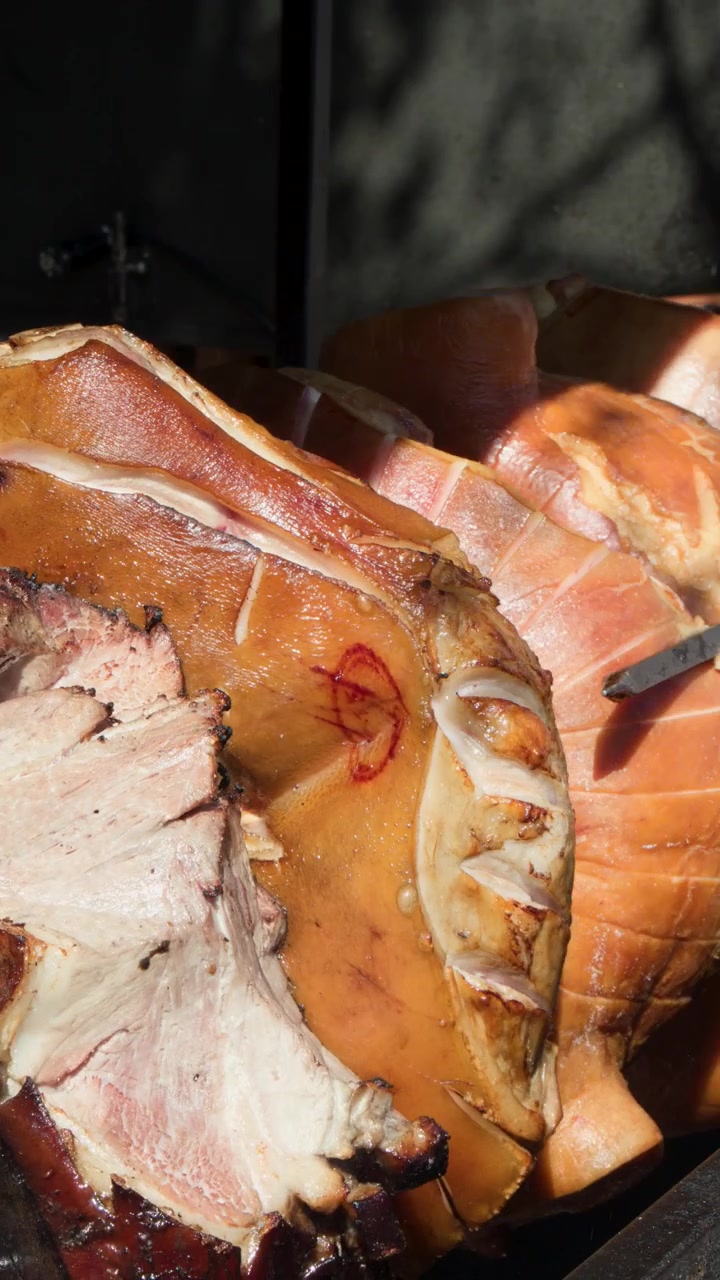 Ganzes Schwein dreht sich am Spieß über offener Flamme, sonnenbeschienen, Freiluftmarkt, traditionelles tschechisches Streetfood