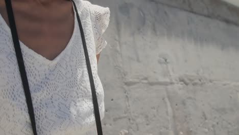 Front-view-of-young-African-american-woman-standing-with-digital-camera-on-beach-in-the-sunshine-4k