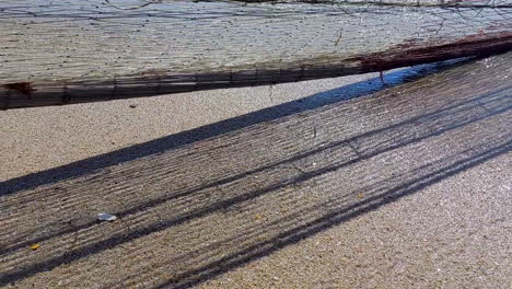 close-up of a fishing net being pulled from the sea, in motion with its shadow cast on the sand