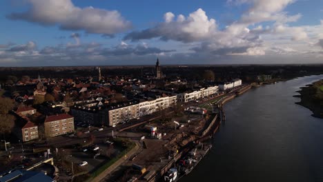 Vista-Aérea-De-La-Orilla-Del-Río-Con-La-Renovación-Del-Muelle-Del-Bulevar-Ijsselkade-Equipo-Pesado-Que-Trabaja-En-El-Muelle-En-Primer-Plano-Y-El-Paisaje-Urbano-Histórico-Más-Amplio-De-Zutphen-Visto-Desde-Arriba-Del-Río-Ijssel