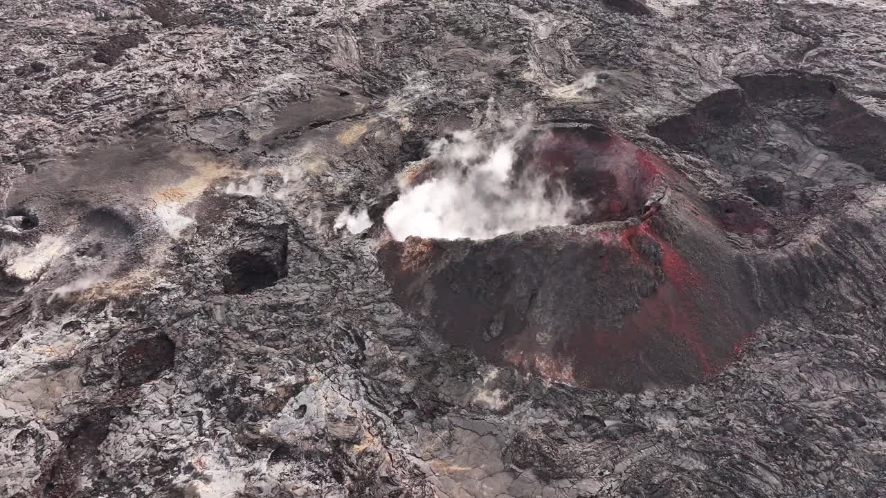 Drone view of volcanic crater in Iceland with visible steam and red lava rocks, stunning aerial view of nature’s raw power