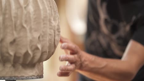 concentrated professional potter carefully shaping stylish clay pot. artist working in workshop with inspiration. finishing touch. selective focus shot