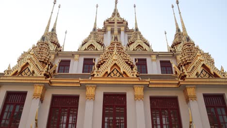 looking-up-at-towering-detailed-golden-pagoda-spires-in-a-buddhist-temple-complex-in-the-Rattanakosin-old-town-of-Bangkok,-Thailand