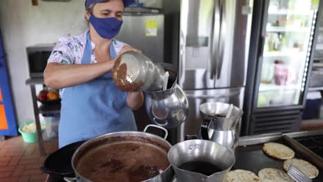 mujer chef vertiendo chocolate caliente en jarras de metal