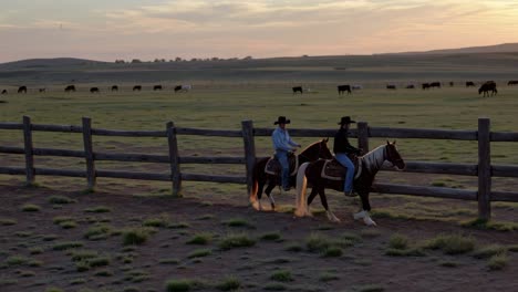 cowboys riding horses at sunrise