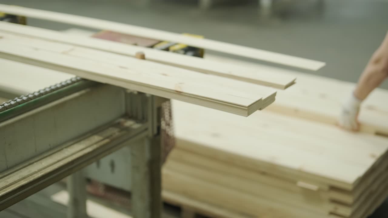 Operaio che impila assi di legno su un nastro trasportatore in una fabbrica