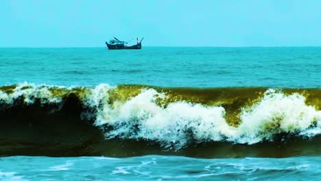 waves crash with the coastline as a fishing trawler boat can be seen out to sea in bangladesh