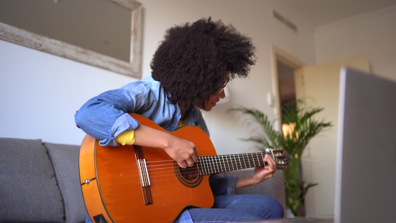 mujer negra positiva tocando la guitarra en casa