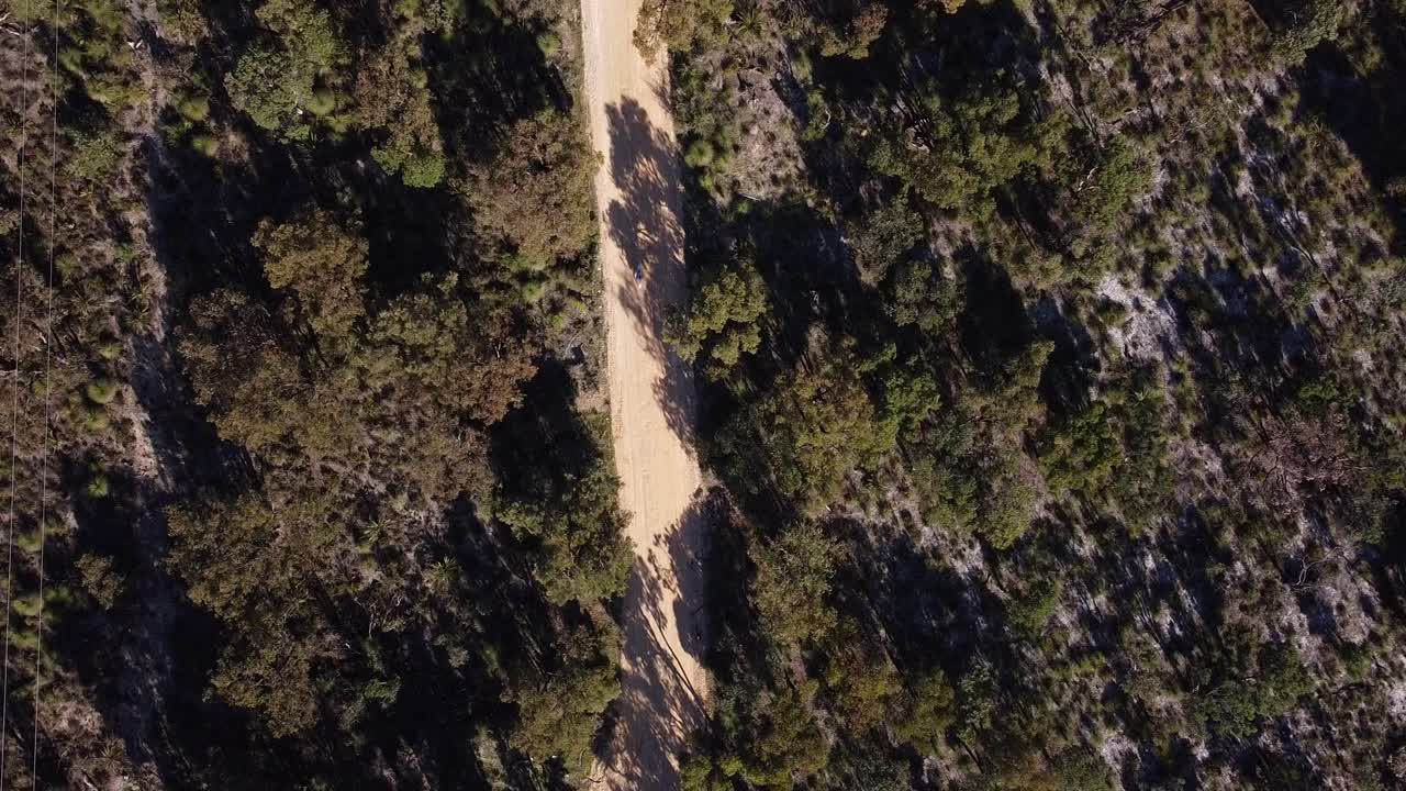 vista de los pájaros por encima de dos corredores de bicicletas de tierra compitiendo a lo largo de la pista de carretera