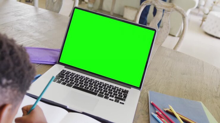 Composition of african american boy on laptop online learning with green screen