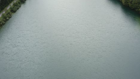 water surface of freibach reservoir in austria approaching the south shore, aerial flyover tilt up reveal shot