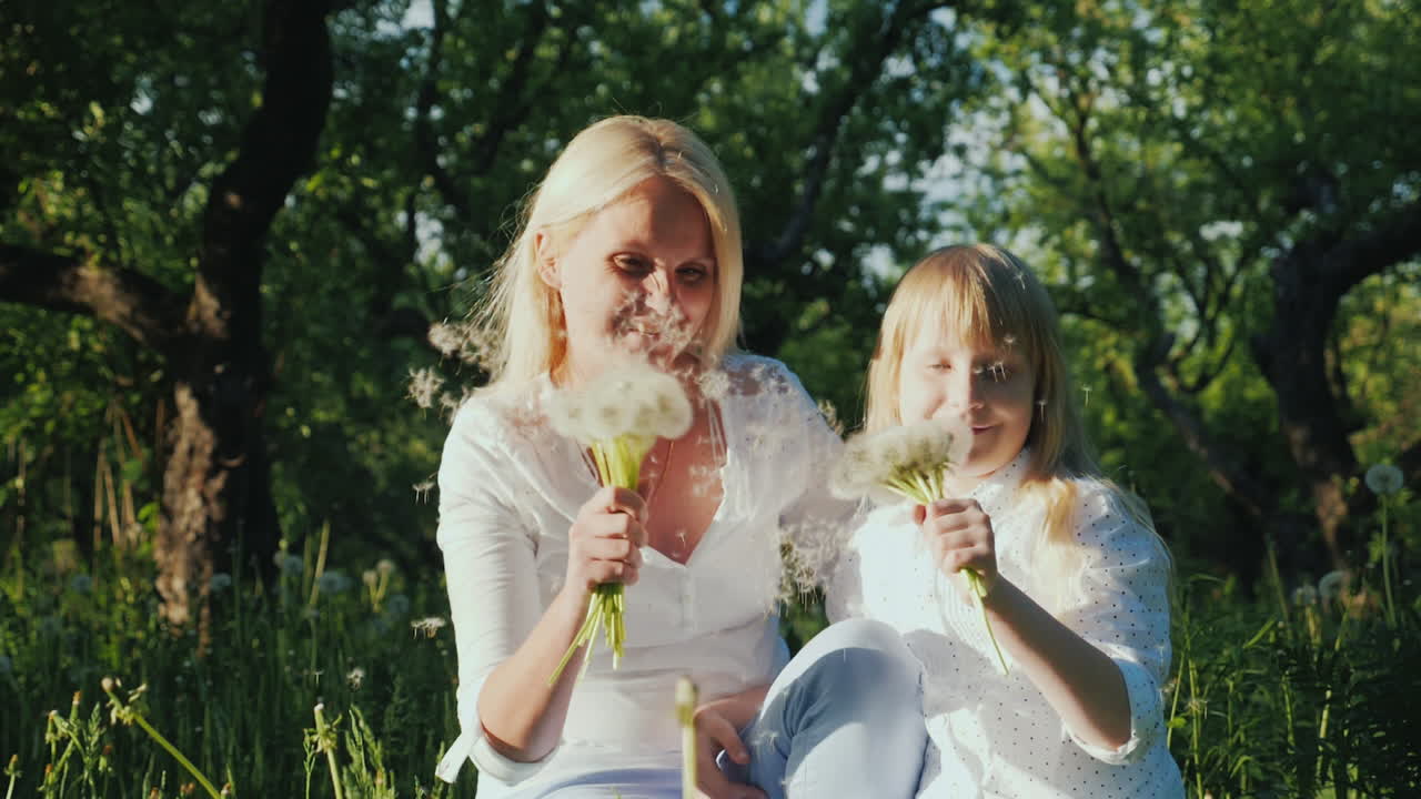 행복한 함께 - 민들레 다발을 가지고 노는 딸과 함께 즐거운 시간을 보내는 여성