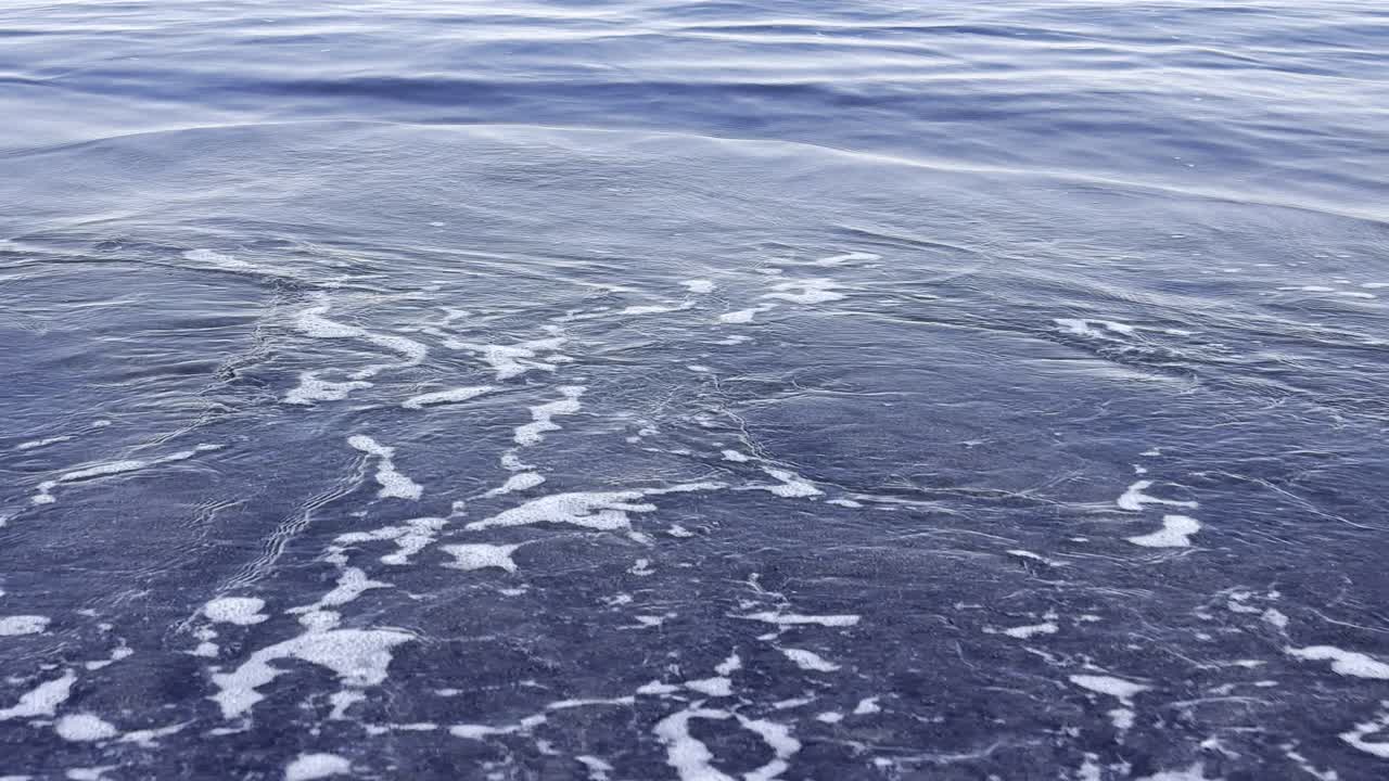Meren aallot lyövät tummahiekkaiselle rannalle
